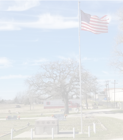 A Cemetery Monument next to Flag pole with a American Flag ontop.